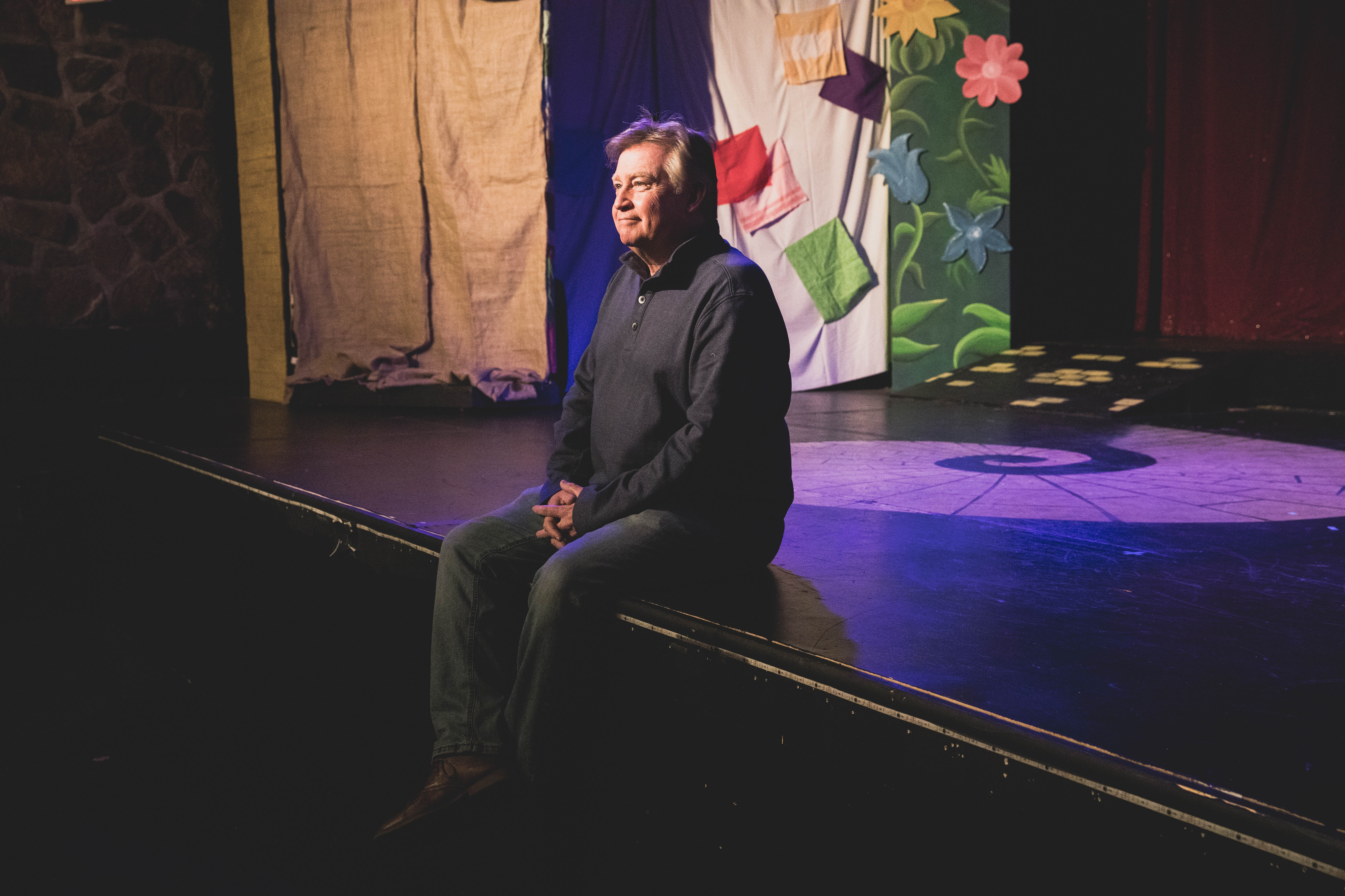 Man sitting on the edge of a Branson live show stage.