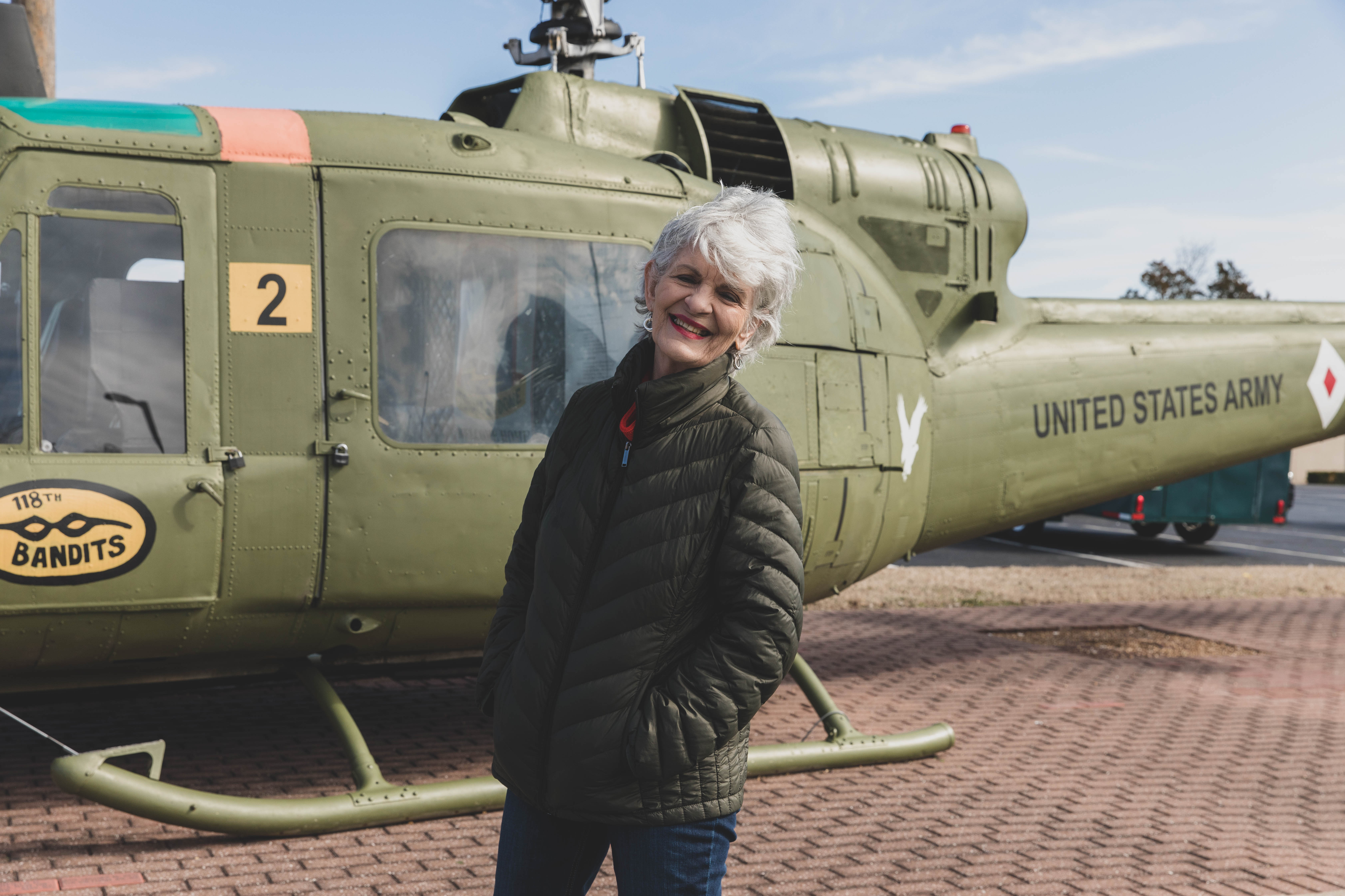 Vietnam Veteran woman standing in front of an army helicopter.