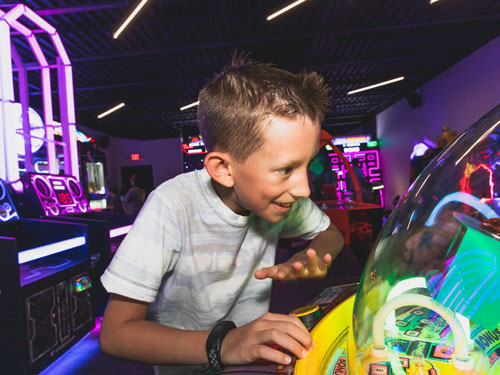 Young boy playing arcade game at Bigfoot Arcade.