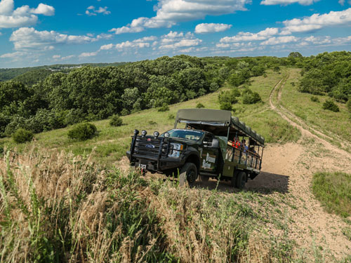 Truck full of passengers driving through a scenic adventure field in Branson.