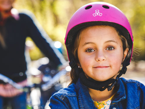 young girl wearing pink helmet and riding a bike with her mom in a nature park in Branson.