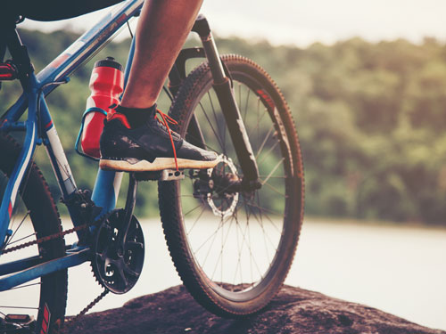 Bicycle and cyclists stopped on the edge of a mountain overlooking green hills in Branson.