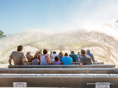 Group of people being splashed with a large wave of water on a boat attraction in Branson.