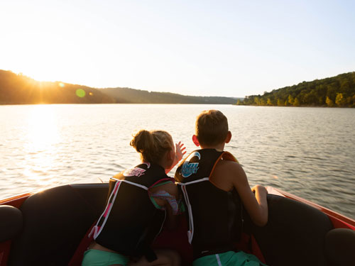 Brother and sister looking out at the lake from their family boat in Branson.
