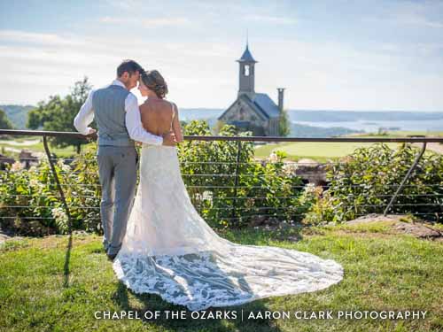 Newlyweds hugging in front of a large chapel on an Ozark golf course.