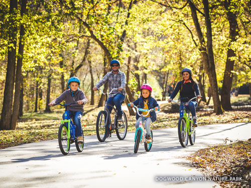 Family of four riding bikes at nature park in Branson.