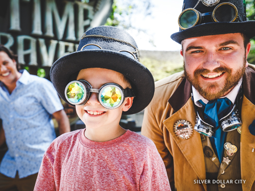 Young boy wearing funny goggles and talking to a theme park worker wearing a vintage costume in Branson.