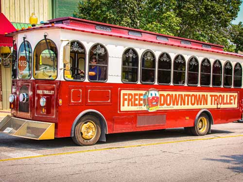 Red free trolley driving through Historic Downtown Branson.