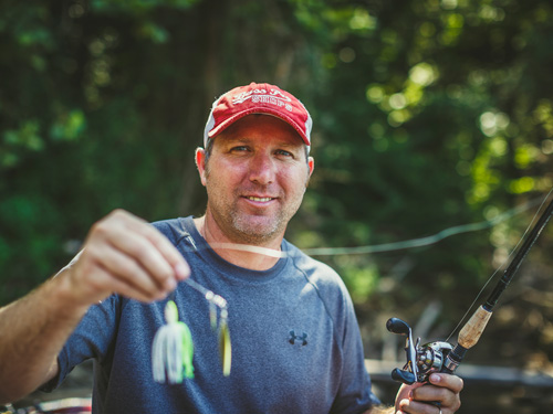 Man holding fishing lure on deck of fishing boat.