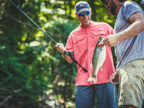 Two men showing off fish on fishing boat in Branson.