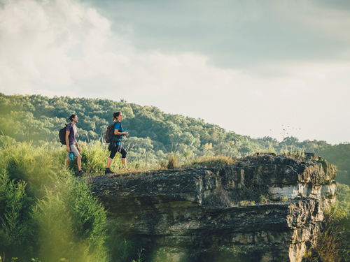 Man and woman standing of the edge of a rock ledge during a scenic hike in Branson.