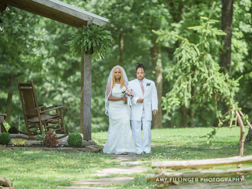 Bride being walked down the aisle at a wooded wedding venue.