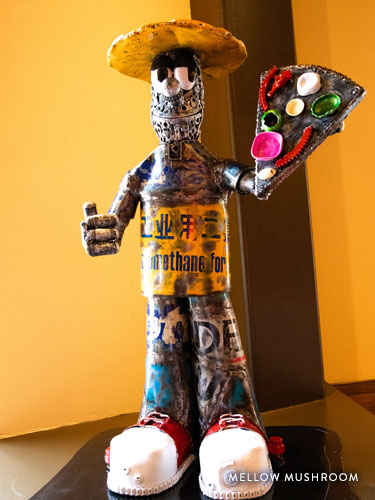Small statue of a man holding a piece of pizza at Mellow Mushroom in Branson.