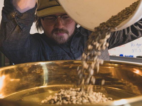 Man pouring coffee beans into a coffee roasting machine in Branson.