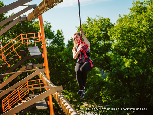 Woman climbing through outdoor ropes course in Branson.