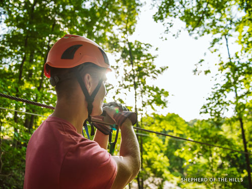 Man riding on outdoor zipline at an adventure park in Branson.