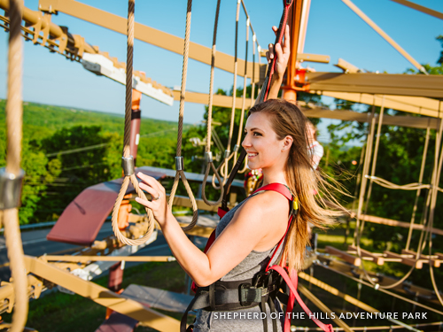 Girl climbing through an outdoor ropes course in Branson.