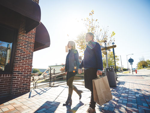 Middle-aged couple holding hands and shopping bags while walking through Downtown Branson.