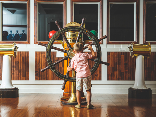 Young boy at a boat steering wheel at Titanic Museum Attraction in Branson.