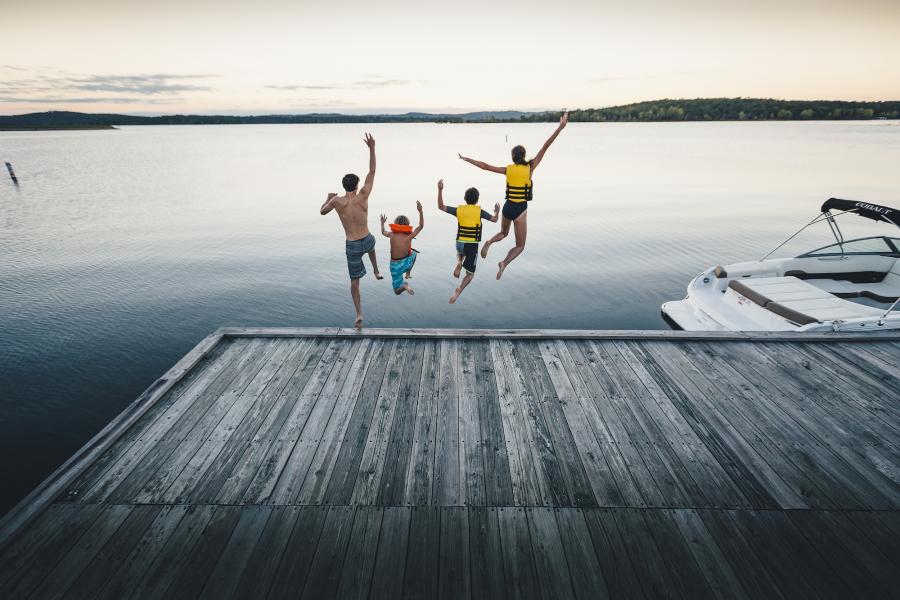 Family of four jumps into Table Rock Lake from dock near boat.