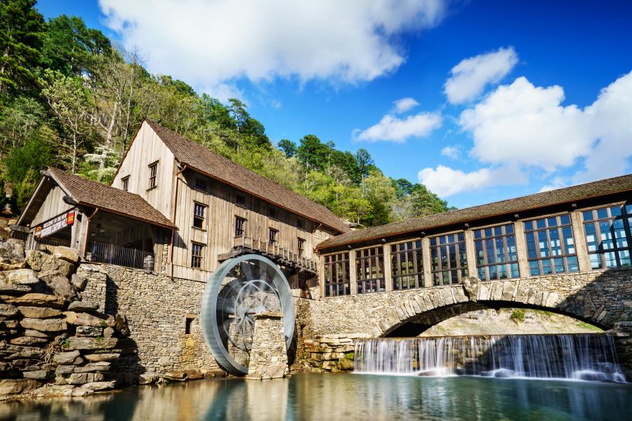 A building and waterwheel next to a waterfall.