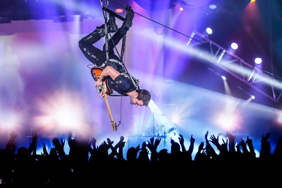 Man hanging upside down playing the guitar.