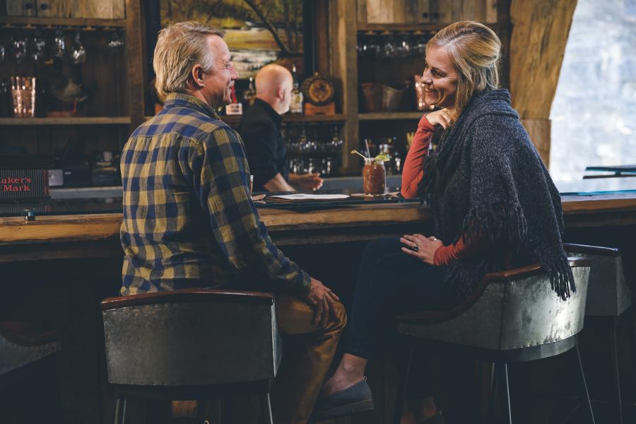 Couple sitting at bar with cocktails.