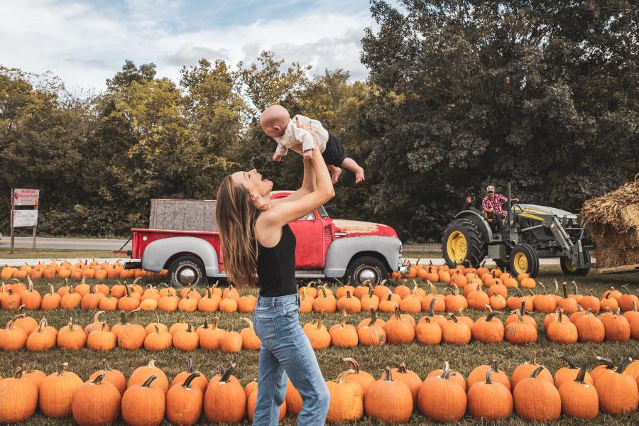 Mom and son at fall festival in branson with pumpkins and tractor