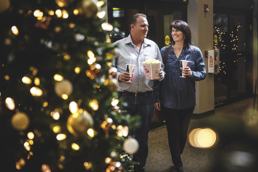 couple walking into show holding popcorn and drink