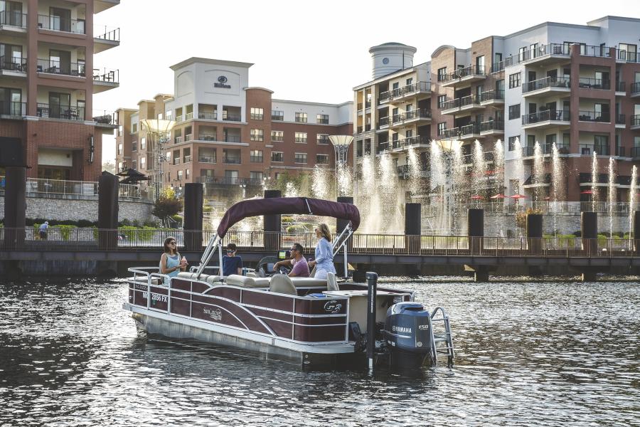 A family on a boat on lake taneycomo in front of the Branson Landing