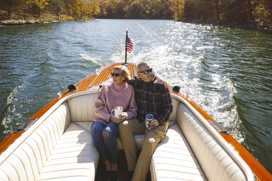 A couple riding in a boat surrounded by fall foliage on Table Rock Lake