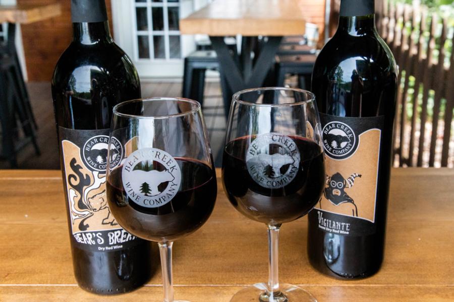 Two wine glasses and wine bottles on a patio at a Branson winery.