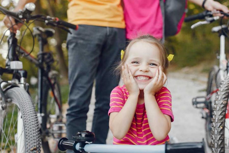 Family of three biking on a nature trail in Branson. Young daughter with pigtails who is leaning on her handlebars in the focus.