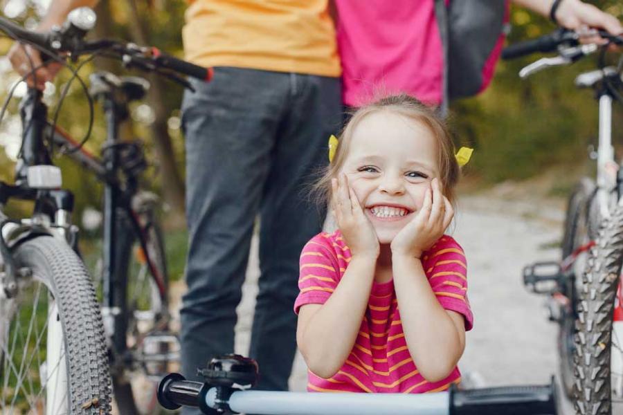 Family of three biking on a nature trail in Branson. Young daughter with pigtails who is leaning on her handlebars in the focus. 