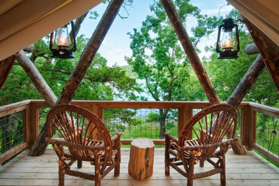 Two wooden chairs on a patio of a tent camping unit at Camp Long Creek in Branson. 