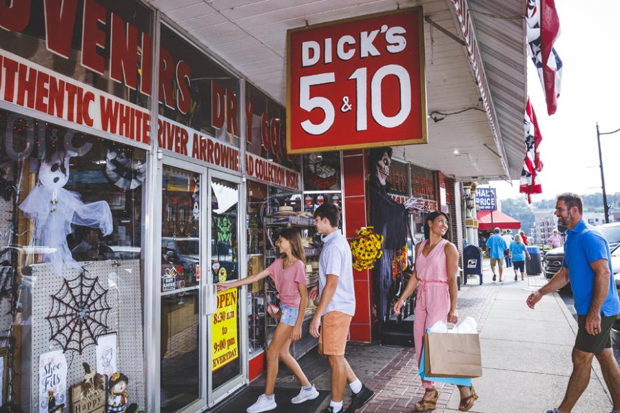 Family of four wearing cute summer clothes and walking into a historic nickle and dime store in downtown Branson. 