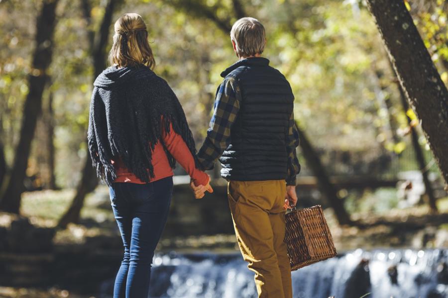 Middle-aged couple holding hands and a picnic basket at a nature park in Branson.