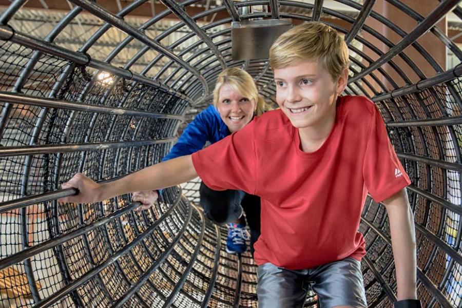 Mom and son adventuring in a rope tunnel at Fritz's Adventure