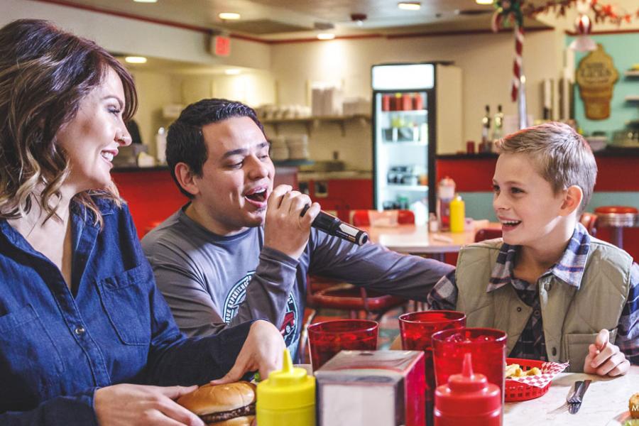 Mother and son being served food by a singing server at a restaurant in Branson.