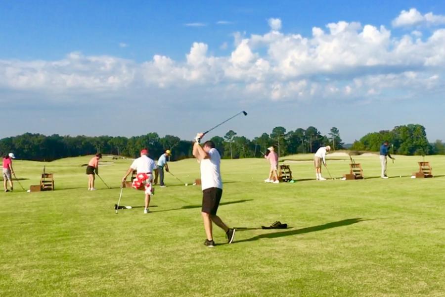 Man practicing golf swing at a crowded driving range in Branson. 