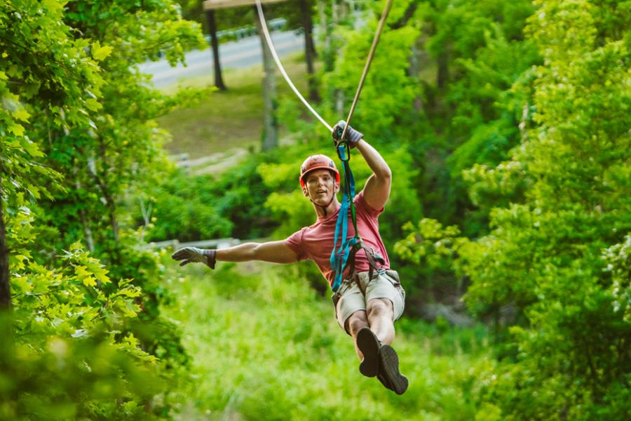Man traveling on zipline through a forest of trees in Branson.