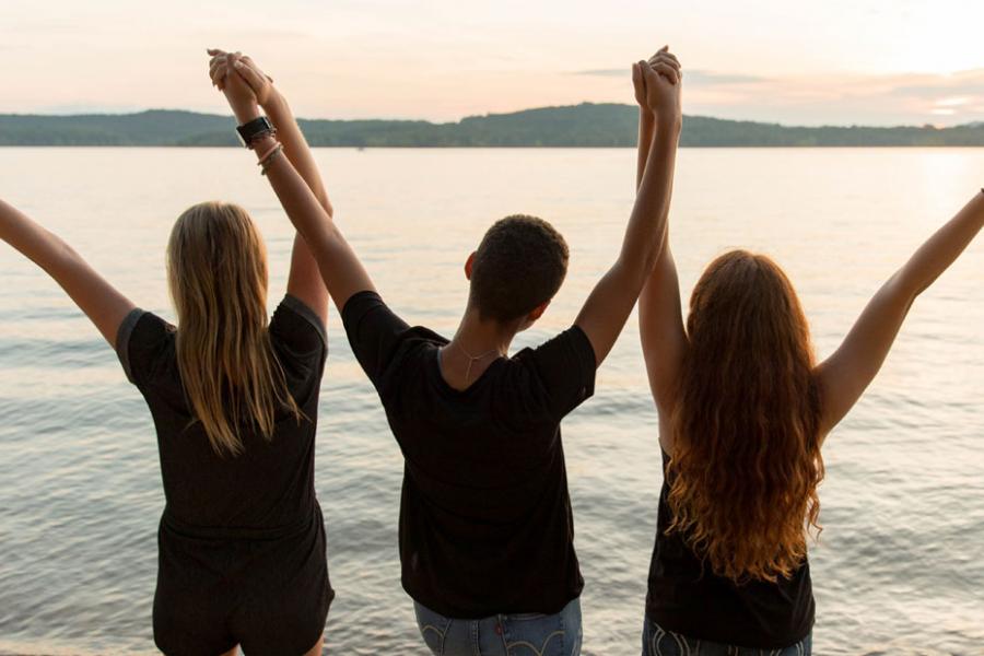 Three girls holding hands and staring into the sunset at Table Rock Lake in Branson.