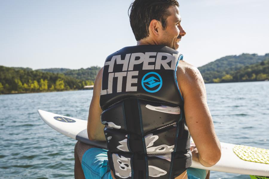 Man sitting on the back of a speed boat while holding a surf board in Branson.