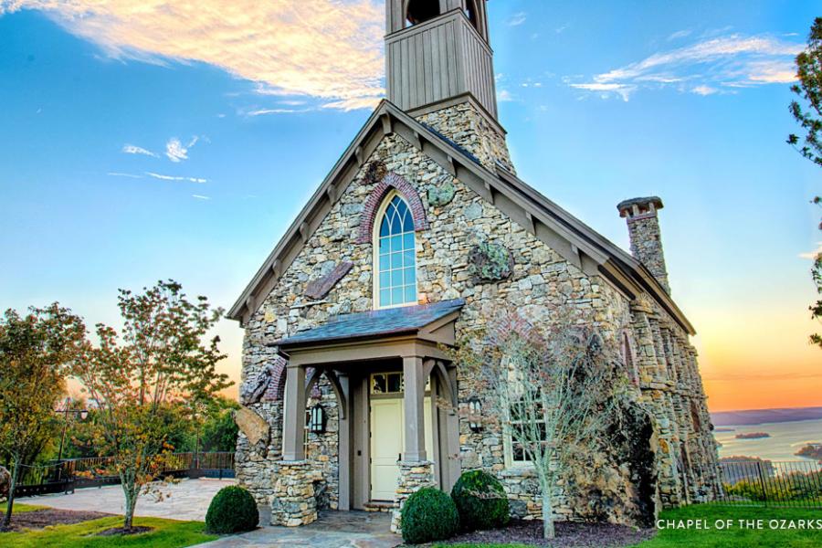 Stunning Chapel in the Ozark Mountains with greenery, flowers, a lake and sunset surrounding it. 