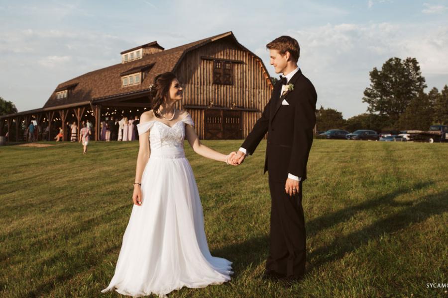 Recently marries couple holding hands in front of a barn wedding venue