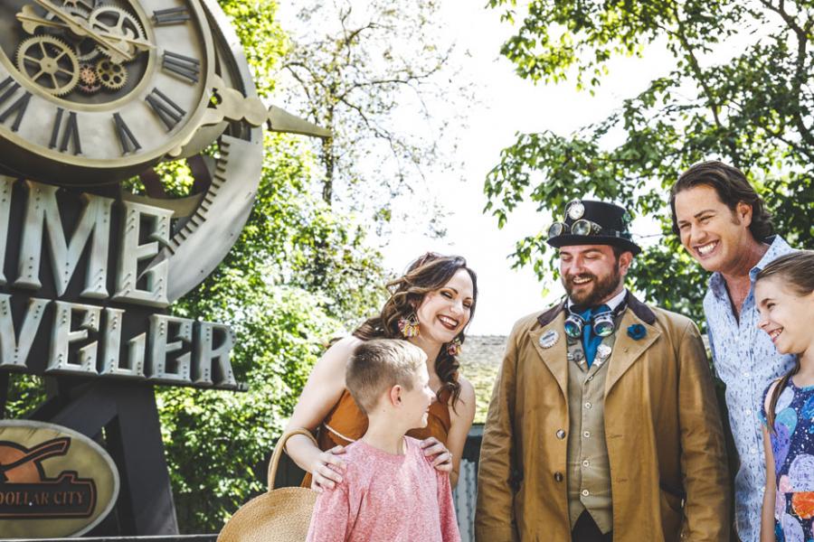 Family of four standing in front of Time Traveler roller coaster with Silver Dollar City staff member.