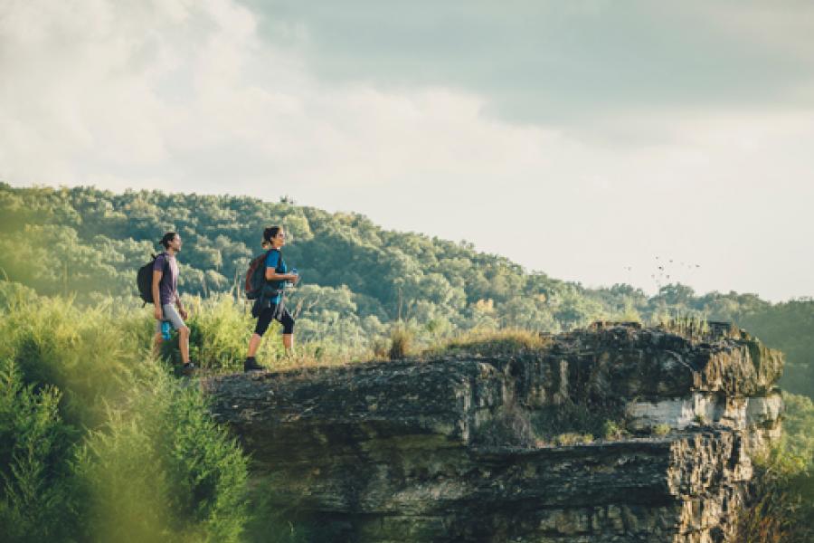 Man and woman standing of the edge of a rock ledge during a scenic hike in Branson.