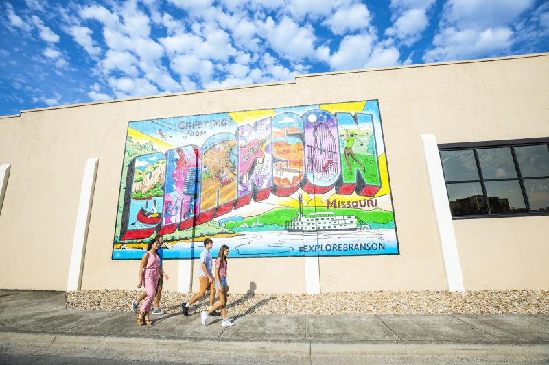 Family walking by Branson Mural in Downtown Branson.