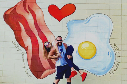 couple posing in front of bacon and eggs mural in springfield, mo