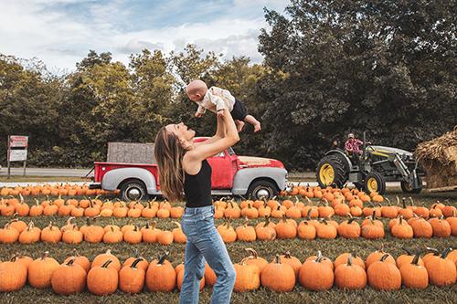 mom holding up baby in a pumpkin match at mckenna family farm in branson